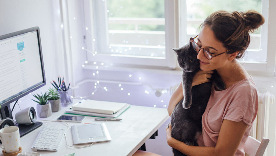 Mujer abrazando a su gato delante del escritorio
