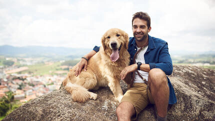 Perro sentado en la montaña con un hombre