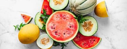 Variedad de melones y sandías cortados sobre una superficie blanca