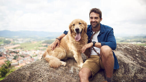 Hombre con un Golden Retriever en una roca