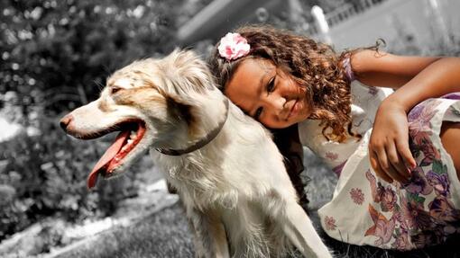 Niña sonriendo junto a un perro