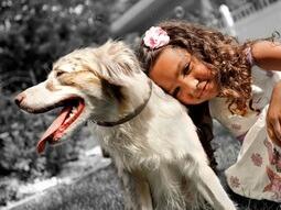 Niña sonriendo junto a un perro