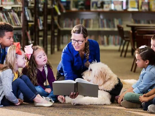 adulto con niños y perro leyendo un libro